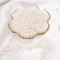 Polished beige ABS imitation pearls for DIY jewelry in a gold-rimmed glass petal tray - Round Shape / 6mm 100 Pcs / Beige