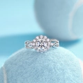 Close-up of D-color moissanite ring with floral halo design on a light blue tennis ball - Adjustable Open / Silver Inlaid Lab-Grown Diamond 1 Carat Ring