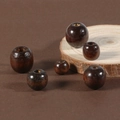 Detailed macro view of dark coffee wooden beads with polished finish on a rustic wood slice - Dark Coffee