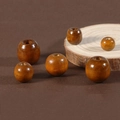 Macro shot of assorted brown wooden beads with visible wood grain and glossy finish - Light Coffee
