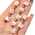 Perle carrée en céramique 8mm avec cerises rouges et tiges bleues dans la main - 8x8mm / Blanc Cerise