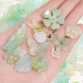 Assorted mint green acrylic floral and heart beads held in hand for DIY jewelry making - 20g per Pack / Green Series