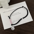Detail of hand-woven black cord bracelet with silver smiley sunflower charm and pink accents - 925 Silver / Pink
