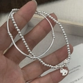 Detalle de pulsera de cuentas en plata S925 con dijes de caballito de madera y flores - Plata 925 / Plata