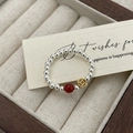 Macro view of silver beaded ring with red agate bead and vintage gold coin charm - Gold