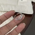 Nahaufnahme eines S925 Sterlingsilber Herzrings, getragen am Finger vor Holzhintergrund - Silber