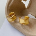 Macro shot of gold matte frosted earrings with irregular wavy edges and C-shape design - Gold