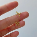 Dettaglio dei piccoli orecchini a lobo a fiocco dorato tenuti in mano per mostrare la misura - Argento 925 / Oro 18K