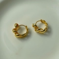 Vista macro di orecchini a cerchio a fune ritorta dorata su superficie chiara - Argento 925 / Oro 18K