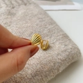 Primer plano de pendientes de concha dorada con textura detallada y acabado pulido - Plata 925 / Oro de 18k