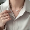Detail of single pearl pendant on golden faceted necklace on model's neckline - 925 Silver / Silver Necklace