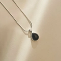 Detail van zwarte agaat druppel hanger aan een zilveren slangenketting met schaduw - 925 zilver / Zwarte agaat
