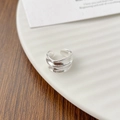 Detailansicht eines unregelmäßigen dreilagigen Silberwellenrings auf weißem Keramikteller - Einzelstück / Silber
