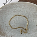 Close-up of S925 sterling silver stamp on golden Figaro chain bracelet on ceramic tray - Figaro Chain / Gold