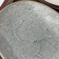 Detailed close-up of polished S925 sterling silver Figaro chain with lobster clasp and tag - Figaro Chain / Silver
