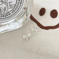 Détail de boucles d'oreilles nœud papillon en argent S925 sur un tissu crème minimaliste - Argent 925 / Argent