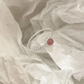 Macro di anello intrecciato in argento S925 con cristallo rosa tondo su carta bianca - Quarzo Fragola
