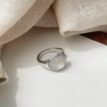 Gros plan d'une bague en argent avec pierre de nacre ovale sur tissu texturé beige - Or Blanc