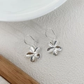 Detail view of silver S925 flower petal earrings on minimalist textured background - 925 Silver / Silver