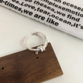 Primer plano de un anillo de nudo plateado con diseño de doble línea en fondo minimalista - Estilo Nudo Abierto / Plata