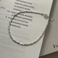 Makro-Detail von S925 Sterling Silber Perlenarmband mit Herzanhänger auf Buchseite - Silber