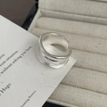 Detailed close-up of a silver-colored wide layered ring with linear texture on fabric - Wide Version