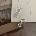 Detailed view of silver hoop earrings with round light blue stones on vintage paper - Aquamarine
