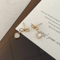 Dettaglio orecchini a fiocco dorati con pendenti a cuore in conchiglia bianca lucida - Argento 925 / Oro