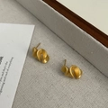 Gros plan de boucles d'oreilles dorées mates avec géométrie pliée 3D sur plateau - Argent 925 / Or