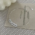 Nahaufnahme des S925 Sterling Silber Kettenarmbands mit Ringen auf einer beigen Karte - 925er Silber / Silber