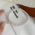 Detail of elegant S925 silver bow pendant and glossy cream pearls on the stylish bracelet - Bracelet / 925 Silver
