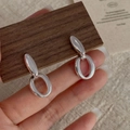 Detailed close-up of S925 sterling silver hollow oval double-hoop earrings on wood - 925 Silver / Silver