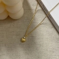 Detail of gold heart pendant with matte texture and small zircon on white fabric - 925 Silver / Gold