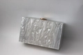 Detail der eleganten Acryl-Clutch mit weißer Marmorstruktur und goldenem Metallverschluss - Weiß