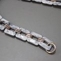 Dettaglio di maglie in resina effetto marmo con inserti dorati e chiusura a molla - Bianco