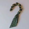 Close-up of elegant dark green polka dot silk scarf wrapped around a gold handbag chain handle - Dark Green White Polka Dot Style
