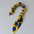 Dettaglio di un foulard di seta intrecciato con una catena di metallo dorato per borse - Stile pois giallo blu navy