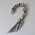 Dettaglio tracolla a catena dorata intrecciata con foulard di seta motivo pied de poule - Stile pied de poule bianco e nero