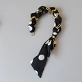 Dettaglio del foulard in seta a pois bianchi e neri intrecciato con catena dorata per borsa - Stile pois grandi bianchi e neri