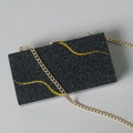 Detail der schwarzen Glitzer-Abendtasche mit goldenen Wellen-Pailletten und Metallkette - Eine Kette