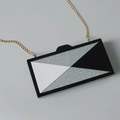 Nahaufnahme der geometrischen Acryl-Clutch mit silbernem Glitzer und goldener Kette - Einzelketten Stil