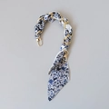 Detail view of blue floral silk scarf entwined with golden metal chain handle strap - Blue and White Floral Style