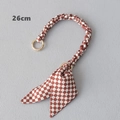 Détail de la poignée de sac à damier rouge de 26 cm avec nœud et anneaux dorés - 26cm / Damier Rouge et Blanc