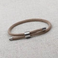Detail view of khaki woven rope bracelet with silver sliding metal charms and toggle ends - Style A (Round) / Khaki