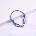 Close-up of blue braided rope bracelet with silver handcuffs buckle on marble base - Light Blue