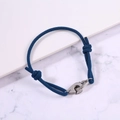 Close-up of blue braided rope bracelet with silver handcuffs buckle and adjustable knots - Teal