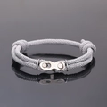 Makro-Detail eines industriellen grauen gewebten Armbands mit Kettenverschluss - Grauweiß