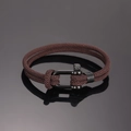 Detail eines dunkelbraun geflochtenen Nylonarmbands mit mattem schwarzem Hufeisenverschluss - Dunkelbraun