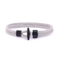 Detail eines grauen geflochtenen Armbands mit mattem schwarzem T-Verschluss und Fixierung - Silbergrau