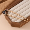Detail of U-shaped golden hairpin with purple shell inlay on a wooden display stand - Irregular Resin Multicolor